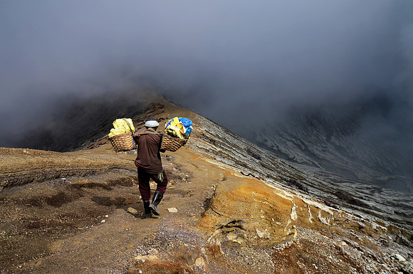 Een zwaveldrager op de vulkaan Kawah Ijen. Hij draagt 80 kg zwavel over 3 steile kilometers.
